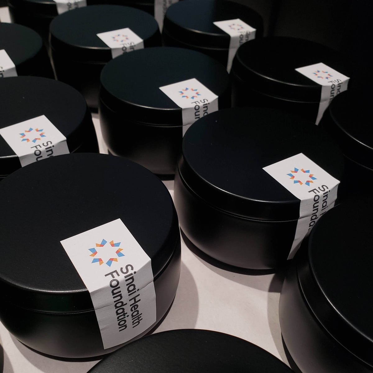 8oz black tin custom candles in production for client & employee gifts