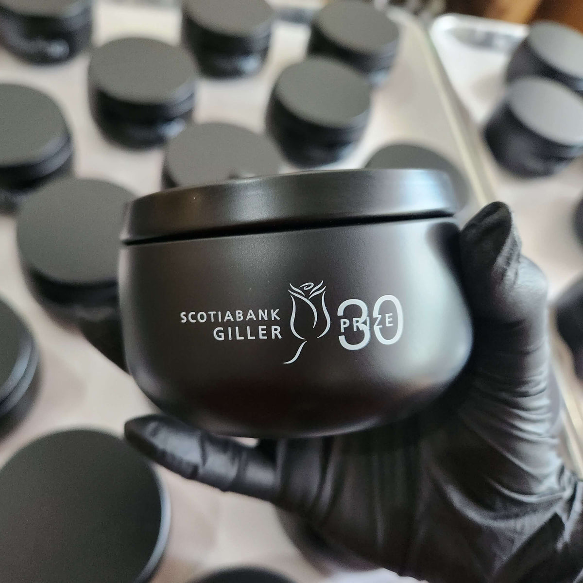 Candle factory production of a custom 8oz black tin candle with logo imprint for corporate gifts